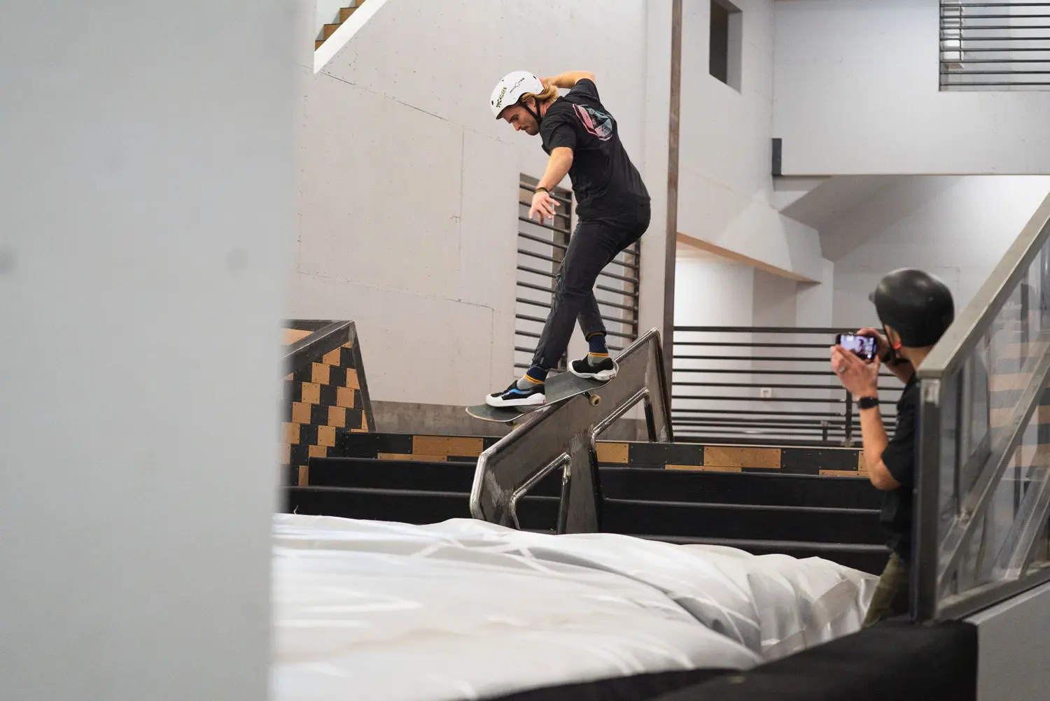 Skater does a back-smith on handrail to airbag